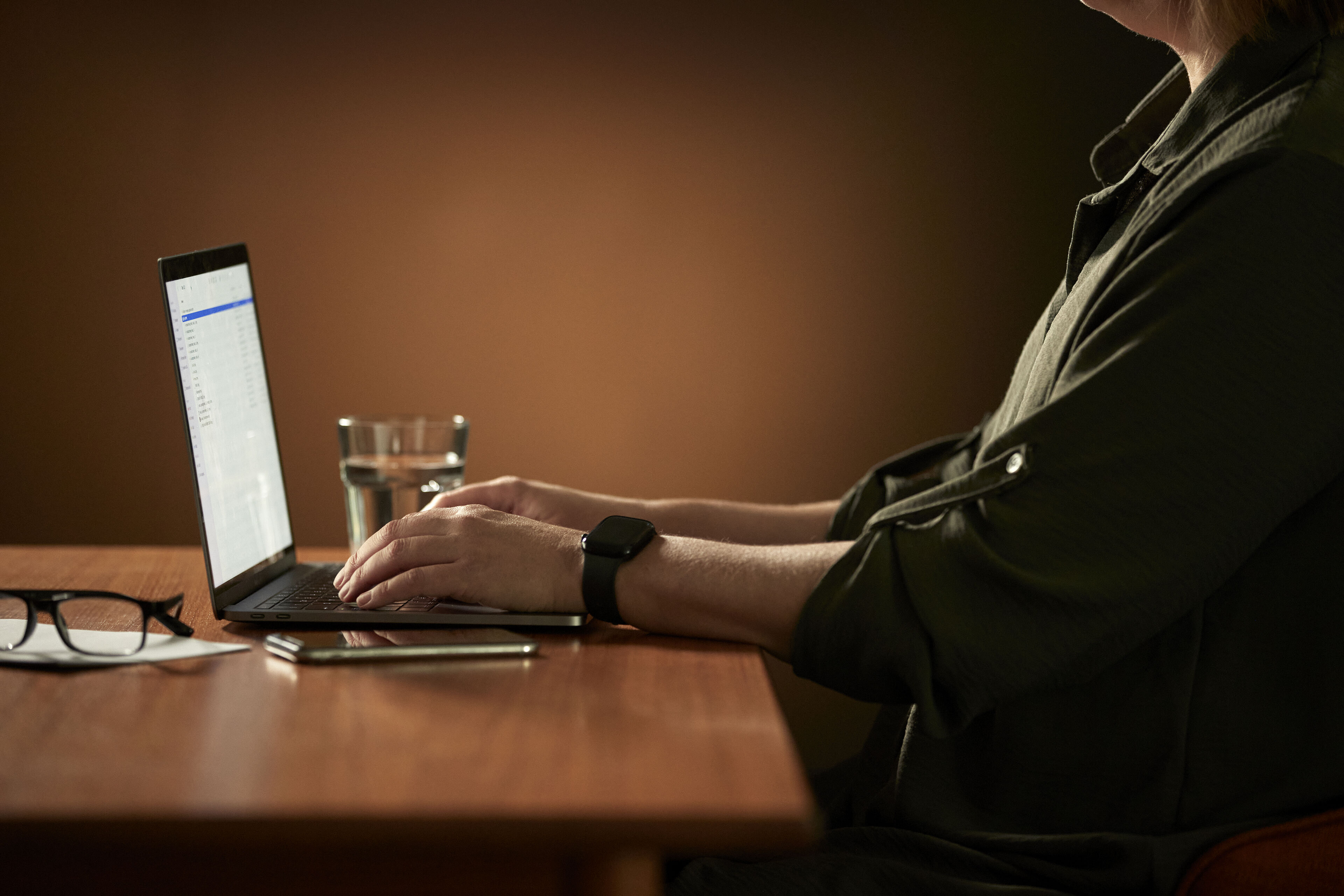 Kvinne som sitter ved en datamaskin og sender tekstmeldinger