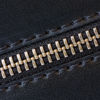 A close-up image of a black faux leather texture featuring a metallic zipper with gold teeth.