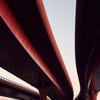 Three red motorway flyovers passing over a railway line.