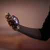 A close-up of a hand holding a mobile phone as the light shines from the phone screen