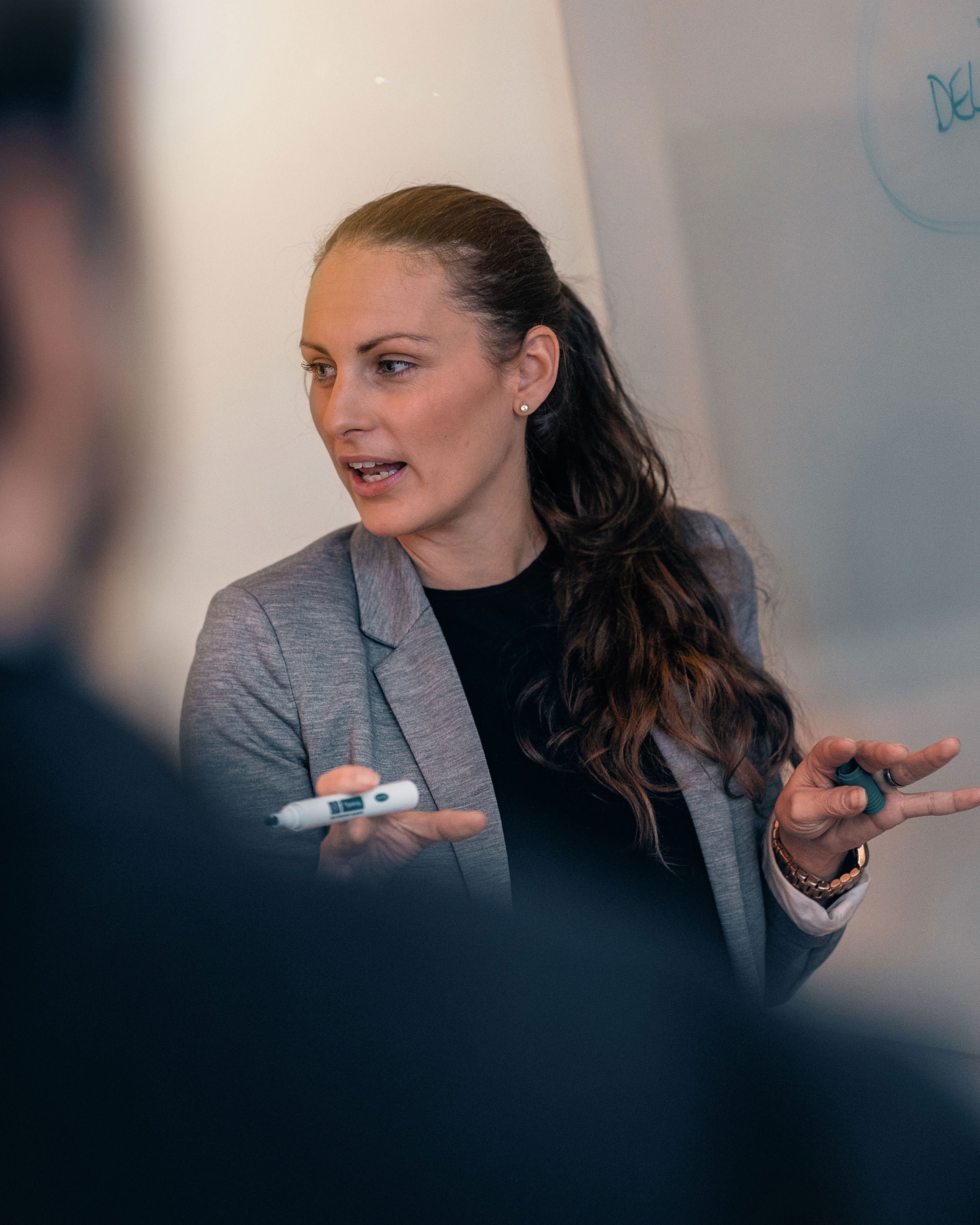 A dark-haired female recycling expert holding a whiteboard marker while educating a class
